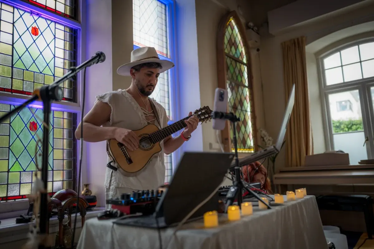 Sasha playing live guitar beside his DJ equipment